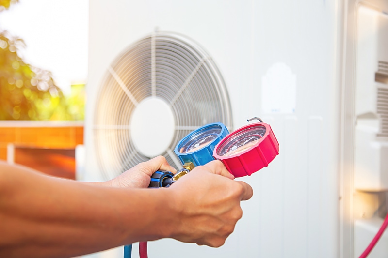 A technician performing seasonal maintenance on an AC unit.