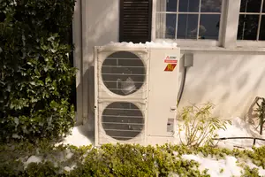 A heat pump unit surrounded by snow, indicating winter HVAC maintenance is required.